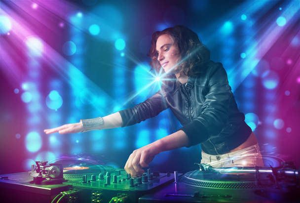 Chica Dj mezclando música en un club con luces azules y moradas
 - Foto, imagen