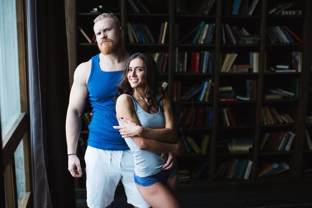 Muscular man with a serious face and a pretty woman smiling - 写真・画像
