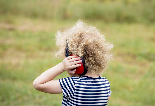 Niño pequeño que usa auriculares bloqueadores de ruido en un concierto al aire libre, lo que evita la pérdida de audición a temprana edad.
. - Foto, Imagen