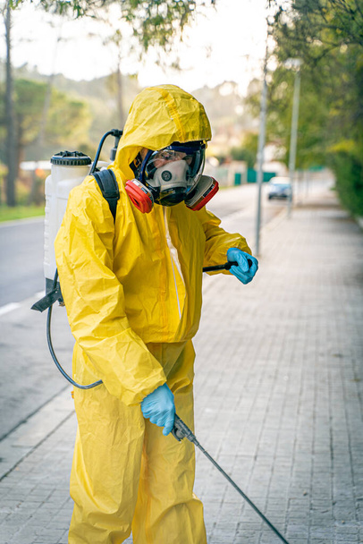 Coronavirus. A sanitation worker wearing a mask and cleaning the streets. Sterilize urban decontaminate city. Disinfecting against to the Coronavirus. Suit protection.  - Fotó, kép