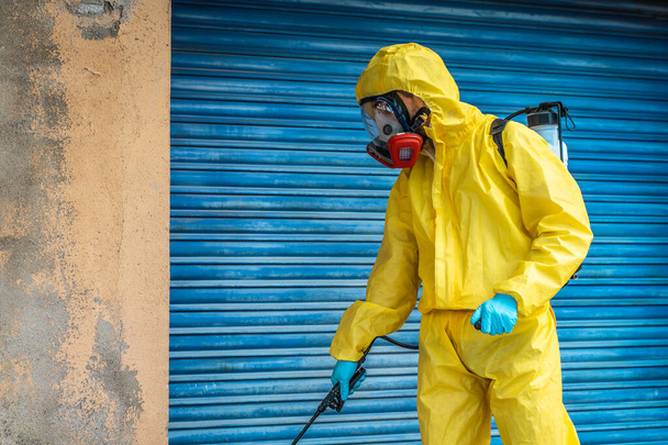 Coronavirus. A sanitation worker wearing a mask and cleaning the streets. Sterilize urban decontaminate city. Disinfecting against to the Coronavirus. Suit protection.  - Foto, Imagem