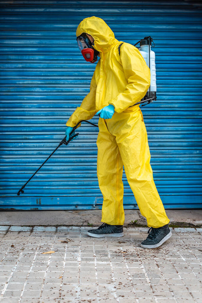 Coronavirus. A sanitation worker wearing a mask and cleaning the streets. Sterilize urban decontaminate city. Disinfecting against to the Coronavirus. Suit protection.  - Foto, Imagen