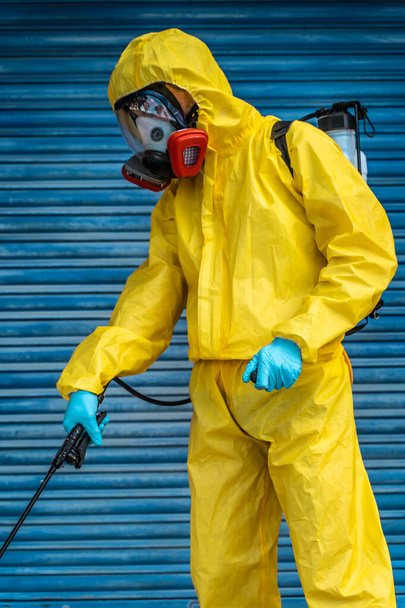 Coronavirus. A sanitation worker wearing a mask and cleaning the streets. Sterilize urban decontaminate city. Disinfecting against to the Coronavirus. Suit protection.  - Foto, Bild