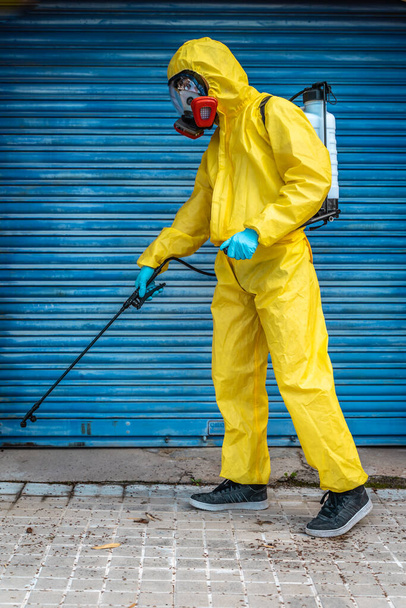 Coronavirus. A sanitation worker wearing a mask and cleaning the streets. Sterilize urban decontaminate city. Disinfecting against to the Coronavirus. Suit protection.  - Photo, image