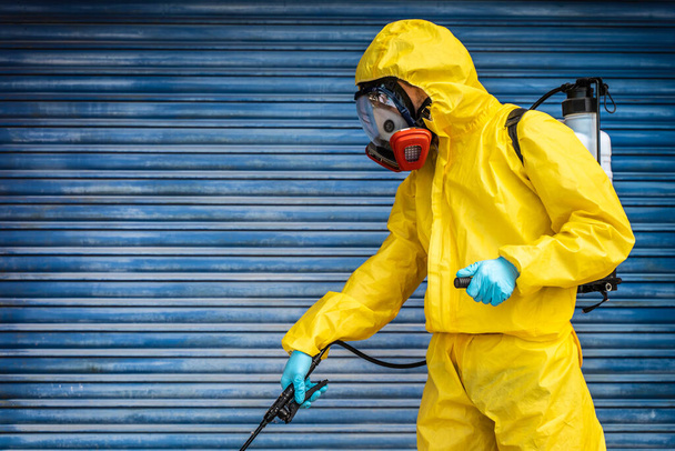 Coronavirus. A sanitation worker wearing a mask and cleaning the streets. Sterilize urban decontaminate city. Disinfecting against to the Coronavirus. Suit protection.  - Foto, afbeelding