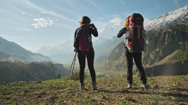 Две женщины-путешественницы стоят над живописной горной панорамой ущелья и фотографируют
 - Кадры, видео