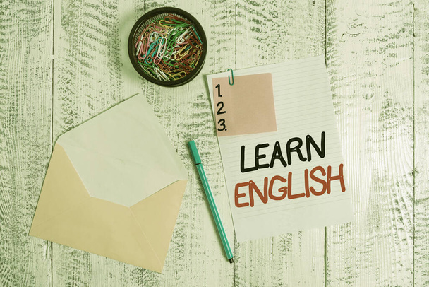 単語ライティングのテキスト英語を学びます。研究によって新しい言語の知識を得るためのビジネス概念封筒シート紙粘着ノートボールペンクリップホルダー木製の背景. - 写真・画像