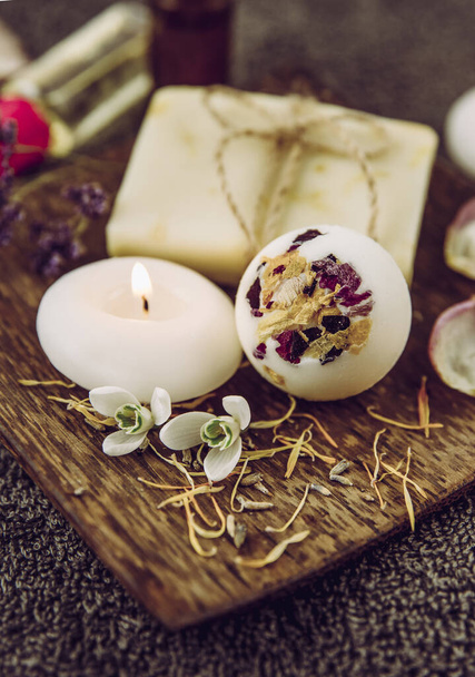 Various relaxation bath products on natural wood tray: creamy bath bomb, bar of soap and aroma oil bottles. Cozy relaxation at home concept. - Photo, Image