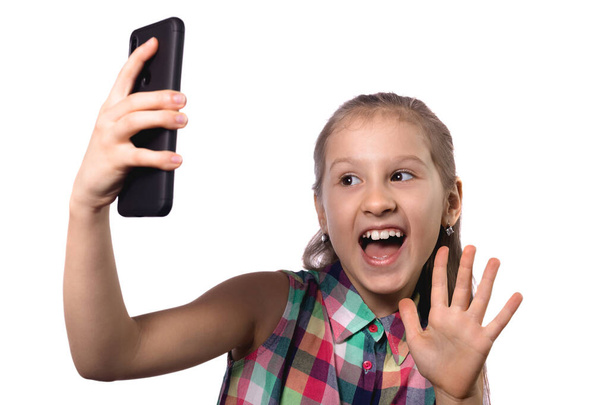 かわいい女の子が彼女の携帯電話で自撮りしている。白い背景のスタジオ写真 - 写真・画像