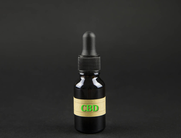 Concepto de aceite de cannabidiol CBD multipropósito. Infusión en frasco de gotero marrón sobre fondo negro oscuro
. - Foto, imagen