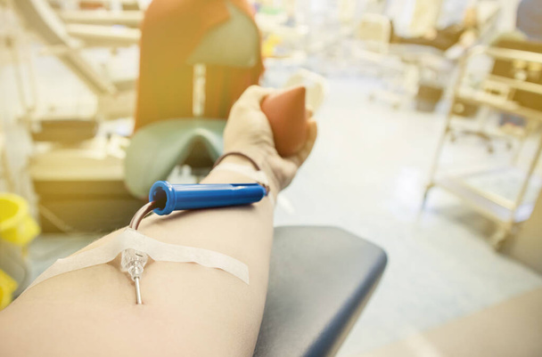 献血装置で女性の腕の手のビューを閉じます.献血者のコンセプト. - 写真・画像