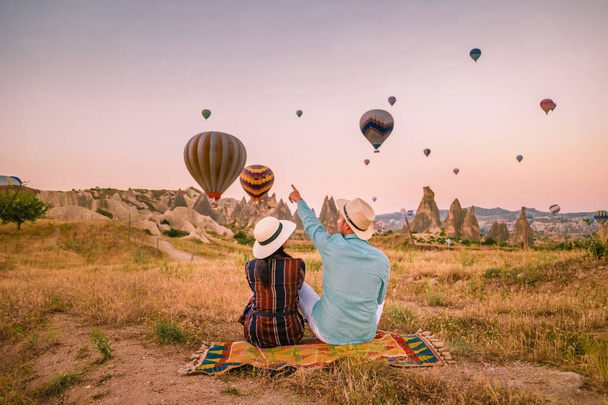 Kappadokien Türkei bei Sonnenaufgang, Paar mittleren Alters Männer und Frauen im Urlaub in den Hügeln von Goreme Kapadokien Türkei, Männer und Frauen bei Sonnenaufgang mit Heißluftballons in Kappadokien - Foto, Bild