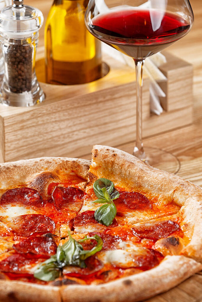 pepperonipizza ja lasi viiniä puupöydällä
 - Valokuva, kuva