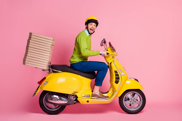 Profile side view of his he nice attractive crazy overjoyed cheerful cheery guy driving moped bringing pile stack pizza order punctuality isolated over pink pastel color background - Photo, Image