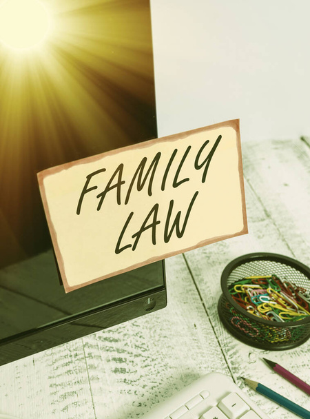 Writing note showing Family Law. Business photo showcasing the branch of law that deals with matters relating to the family Note paper taped to black computer screen near keyboard and stationary. - Photo, Image