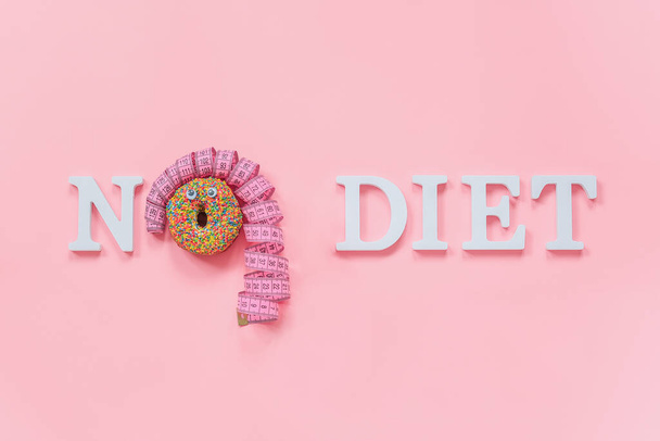 Text No diet and abstract funny face of woman from donut with eyes and hair from centimeter tape on plate on pink background. Concept International No Diet Day, 6 may Top view Flat lay Copy space. - Photo, image