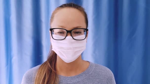 Girl with medical mask to protect her from virus. Coronavirus pandemic. Woman with mask standing . People being hospitalized, diagnosed, often put in carantine isolation to stop spreading Corona. - Video, Çekim