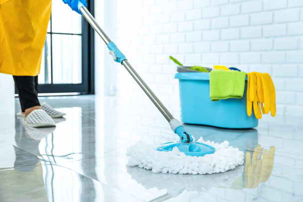Wife housekeeping and cleaning concept, Happy young woman in blue rubber gloves wiping dust using mop while cleaning on floor at home. - Foto, imagen