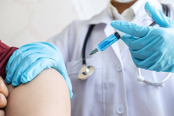 Doctor making injection vaccination patient to prevent pandemic of the disease, flu or influenza virus in clinic. - Photo, Image