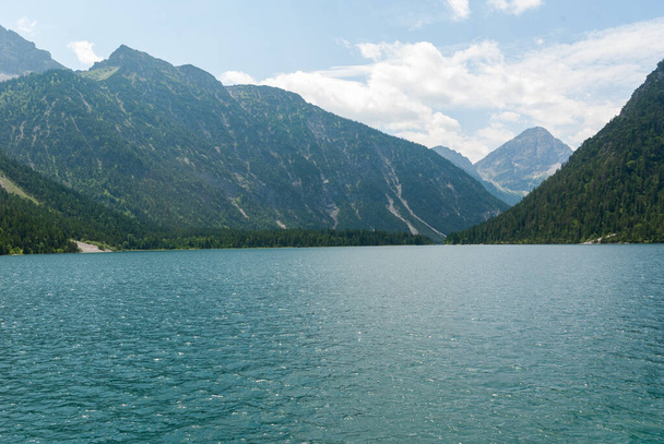 selektiver Fokus, ein alpiner blauer See an der Grenze zu Deutschland mit Bergen - Foto, Bild