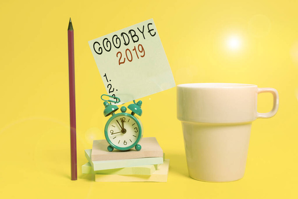Concept d'affaires pour exprimer de bons vœux lors de la séparation à la fin de l'année Alarme horloge tasse de café note bloc-notes empilés crayon fond coloré
. - Photo, image