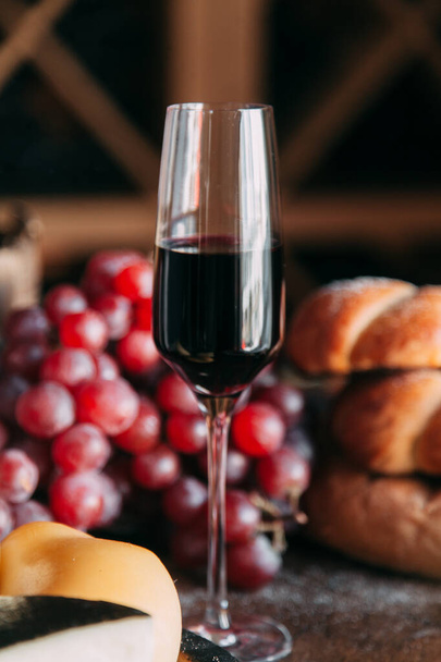 A slice of hard Parmesan cheese and a bottle of wine. Composition with cheese, wine and bread.  - Foto, imagen