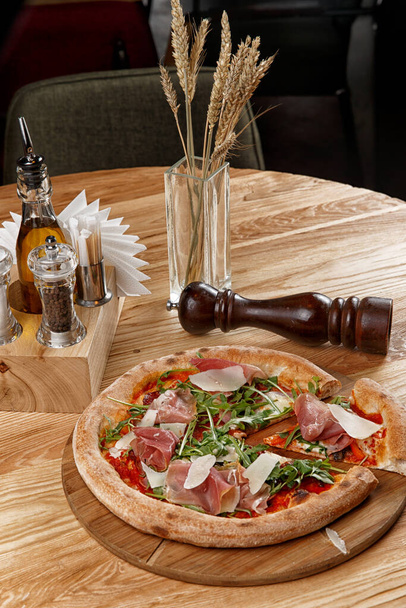 pizza with jamon and herbs on a wooden table - Photo, Image