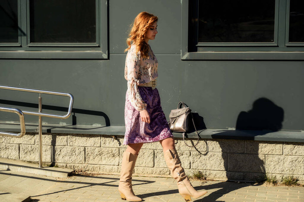 Full-length photo of a fashionable glamorous beautiful woman with long hair on the background of the steps of the building in the spring in the sun in bright weather. - Foto, imagen