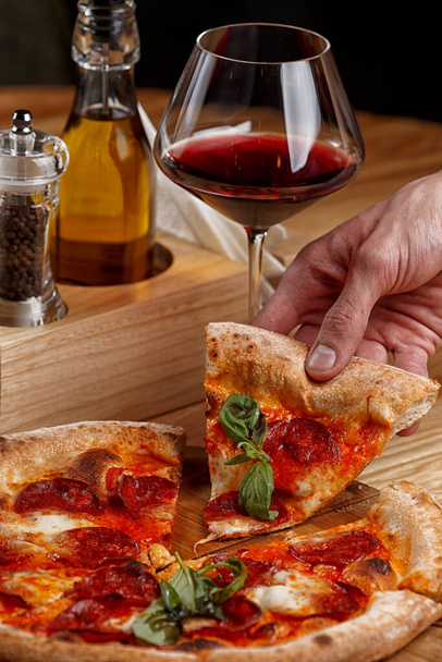 pizza de pepperoni y una copa de vino en una mesa de madera
 - Foto, imagen
