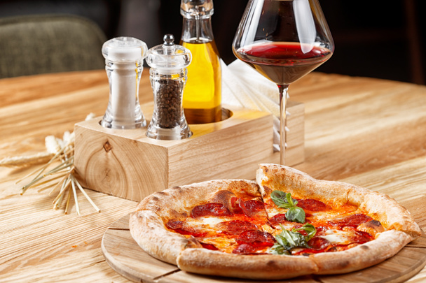pepperoni pizza a sklenice vína na dřevěném stole - Fotografie, Obrázek