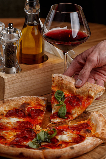pepperoni pizza a sklenice vína na dřevěném stole - Fotografie, Obrázek