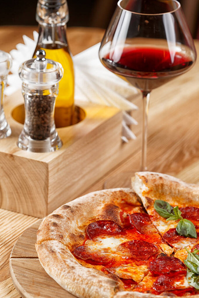 pizza al salame piccante e un bicchiere di vino su un tavolo di legno
 - Foto, immagini
