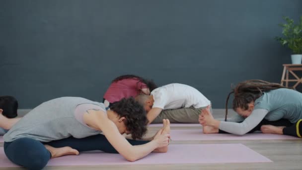 Female yoga teacher speaking showing asanas to group of people in class - Felvétel, videó
