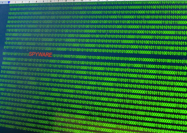 Rode inscriptie Spyware in kwaadaardige computercode geschreven door een hacker. Foto van een computerscherm met een gevaarlijke programmacode. - Foto, afbeelding