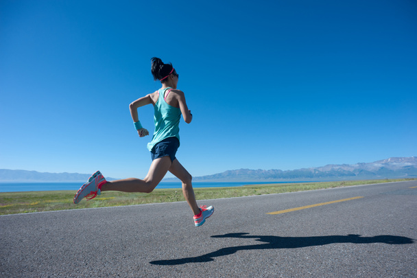Νεαρή γυναίκα γυμναστικής τρέχει στην ανατολή του ηλίου παραθαλάσσιο μονοπάτι - Φωτογραφία, εικόνα