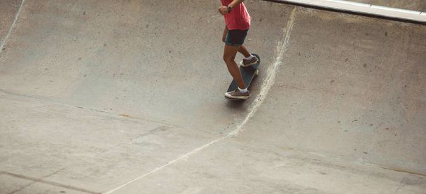 Legs of fit female skateboarder skating at urban skate park - 写真・画像