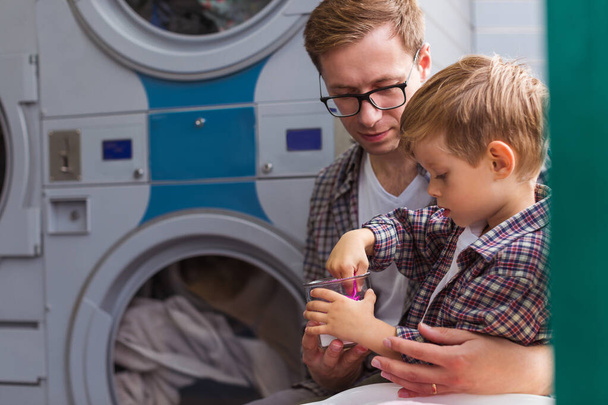 man and son doing laundry at high street store dry cleaning - Фото, изображение