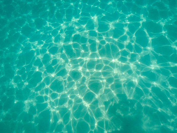 Ondulaciones o reflejos de la luz del sol bajo el agua sobre el suelo arenoso del océano poco profundo, el mar Mediterráneo, la escena natural
 - Foto, imagen