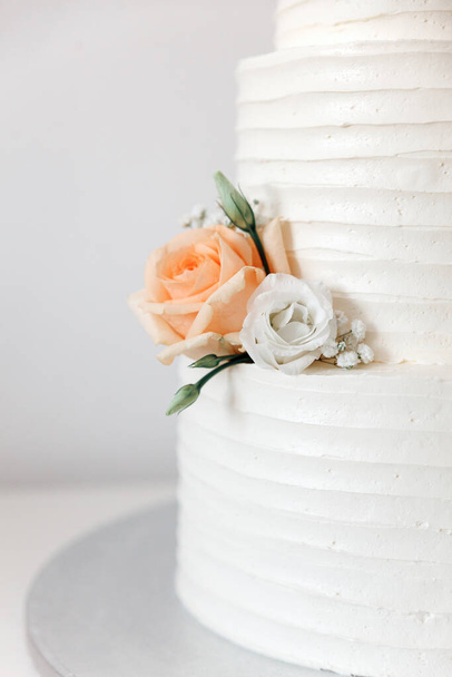 White cream wedding cake decorated with flowers and leaves close-up white background - Zdjęcie, obraz