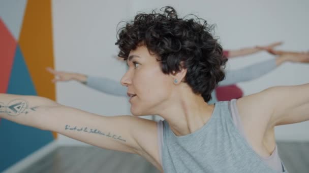 Yoga teacher demonstrating asanas speaking during group class in studio - Felvétel, videó
