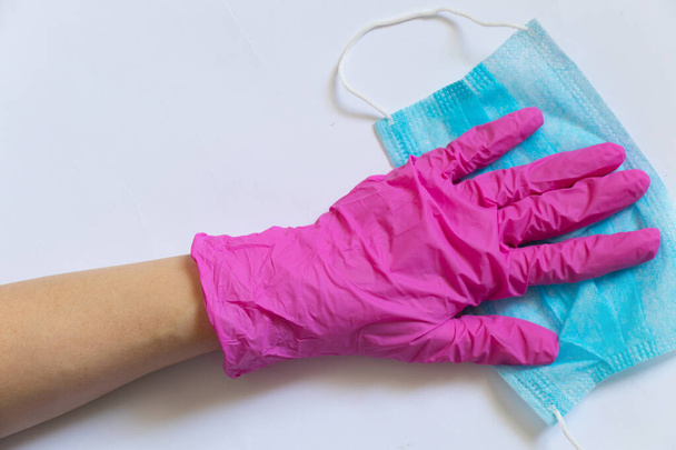 máscara azul protectora médica y mano femenina en guantes negros sobre un fondo blanco de cerca
 - Foto, imagen