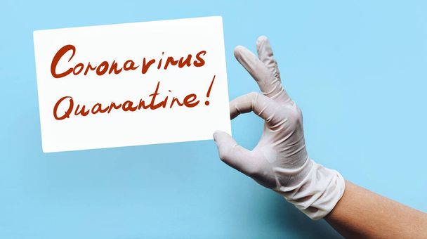 Chinese Coronavirus outbreak - 2019-nCoV concept. A hand of doctor in a medical rubber glove holds a white sheet of paper with the inscription: Coronavirus Quarantine! Blue background. MERS-Cov. - Zdjęcie, obraz