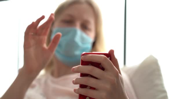 quarantaine pour l'épidémie de coronavirus. Une femme infectée dans un masque discute via un lien vidéo sur un smartphone
. - Séquence, vidéo