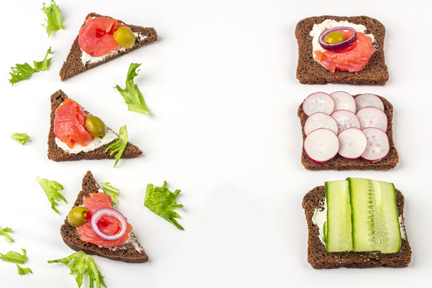 Appetizer, open sandwich with different toppings: salmon and vegetables on white background. Traditional Italian or Scandinavian cuisine. Healthy eating. Flat lay, copy space for text  - Foto, imagen