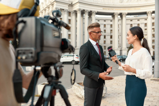 Journalism that is independent, honest, and dignified. Cameraman and news reporter interviewing politician. Journalism industry, live streaming concept. - Photo, Image