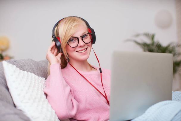 Girl student happy to communicate with friends headphones via Internet. home schooling, work and study, new knowledge. happy teen sitting in chair with computer. women looking at laptop and smiling. - 写真・画像
