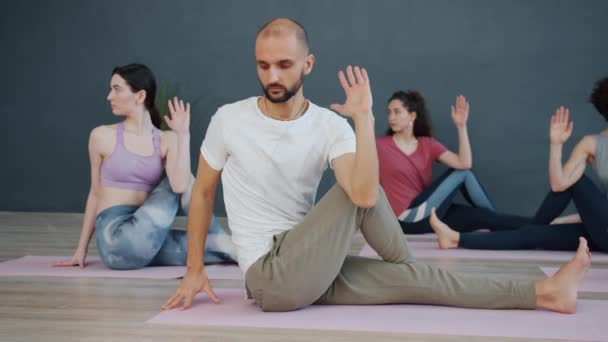 Group of yoga students doing twisting exercises on mats focused on practice - Video, Çekim