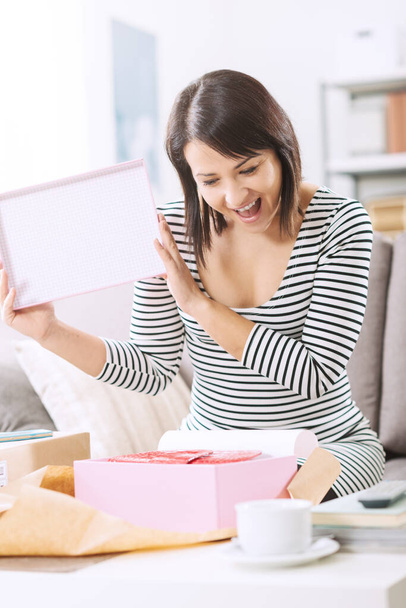 Happy woman unboxing a parcel containing a fashion bag, online shopping, delivery and customer satisfaction concept - Φωτογραφία, εικόνα