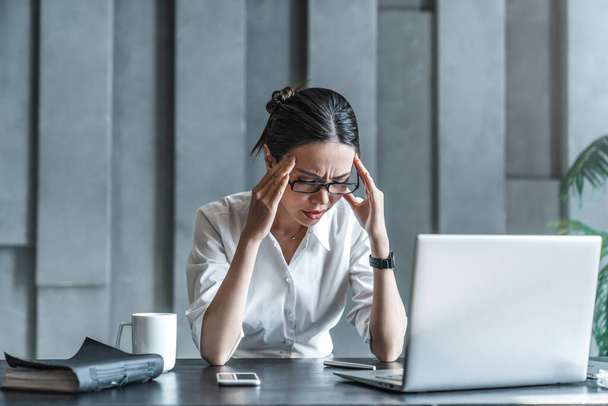 Young woman working on laptop having headache - Photo, Image