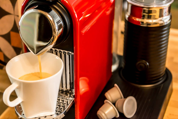 Fare il caffè: primo piano di una macchina da caffè a base di tazza rossa, versando il caffè in una tazza bianca
 - Foto, immagini